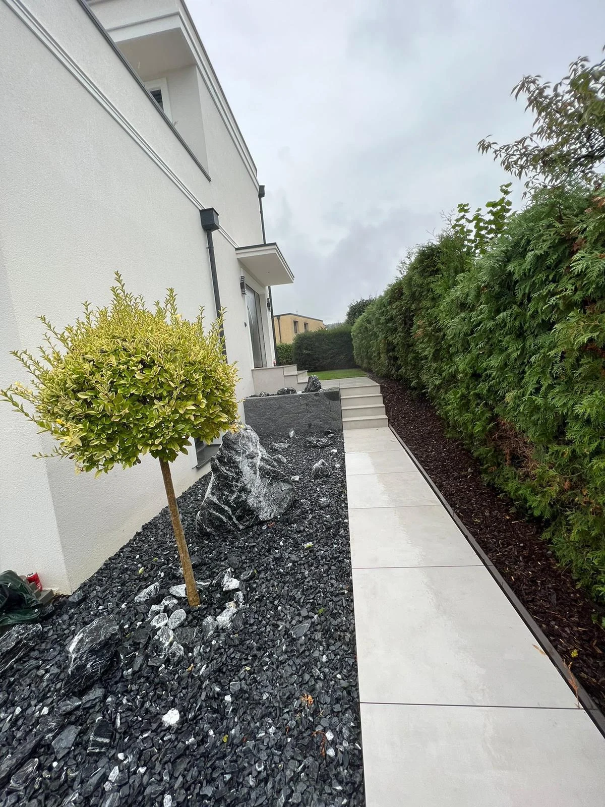 Heller Gartenweg neben dunklem Schotterbeet