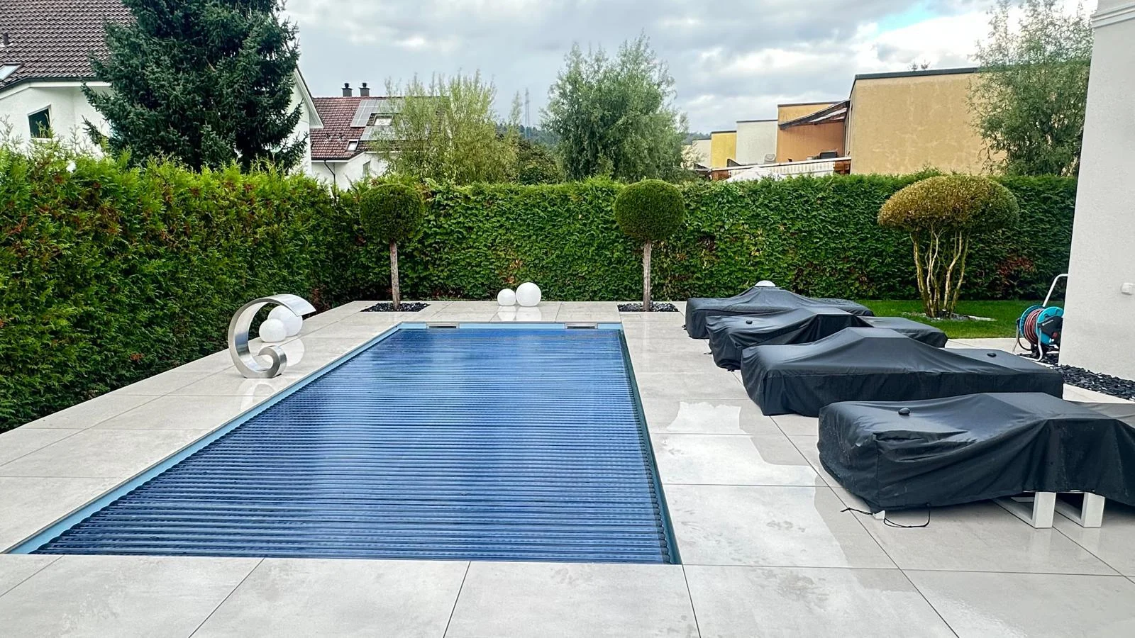 Poolterrasse mit Hecke und Kugelbäumen