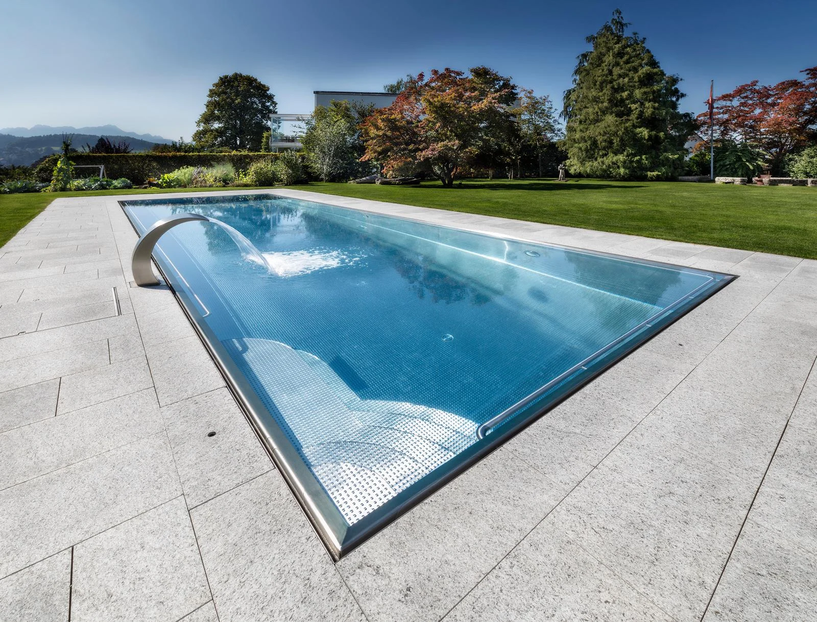 Gartenpool mit Wasserschwall und Plattenumrandung