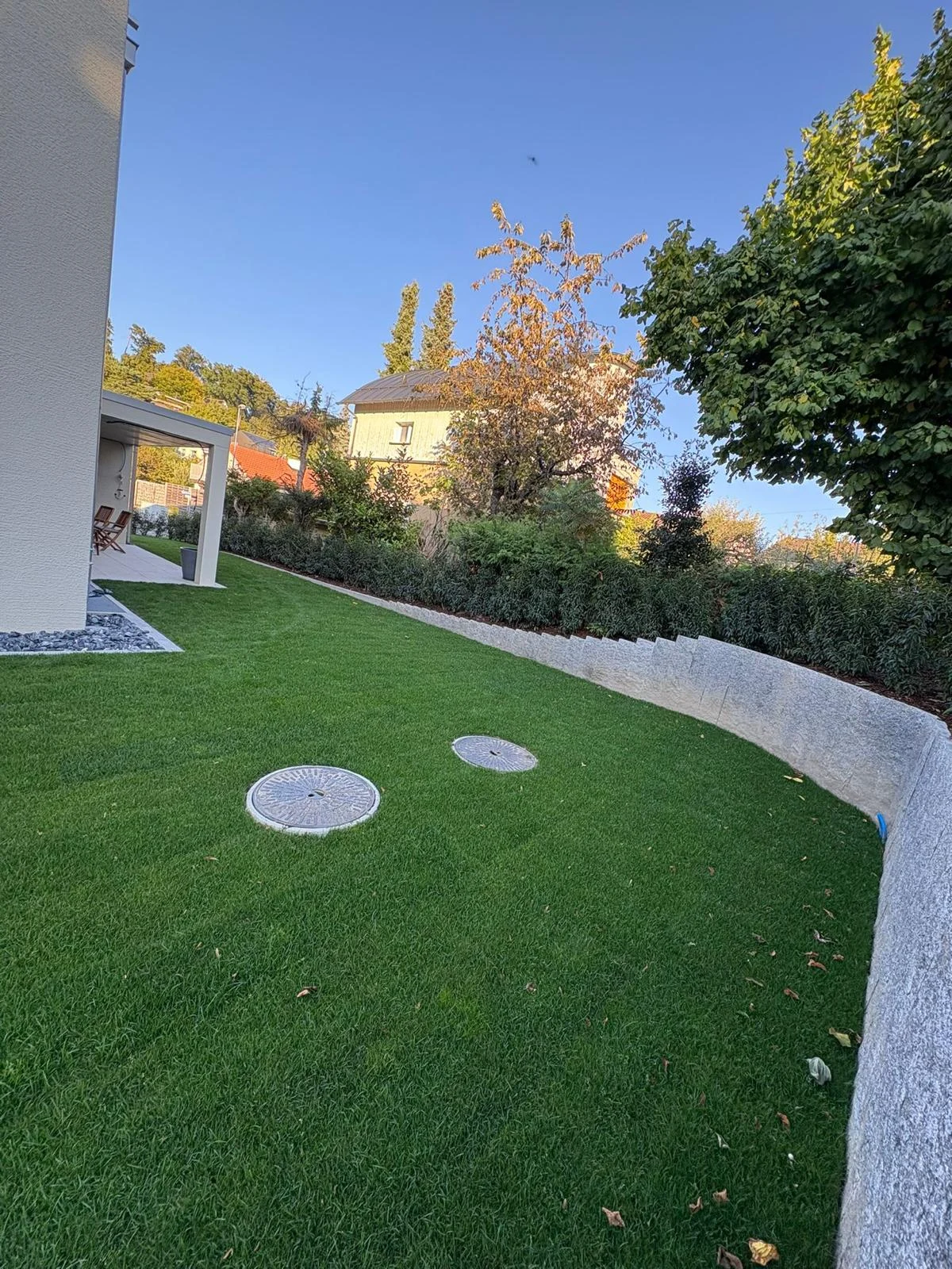 Geschwungene Gartenmauer entlang der Rasenfläche