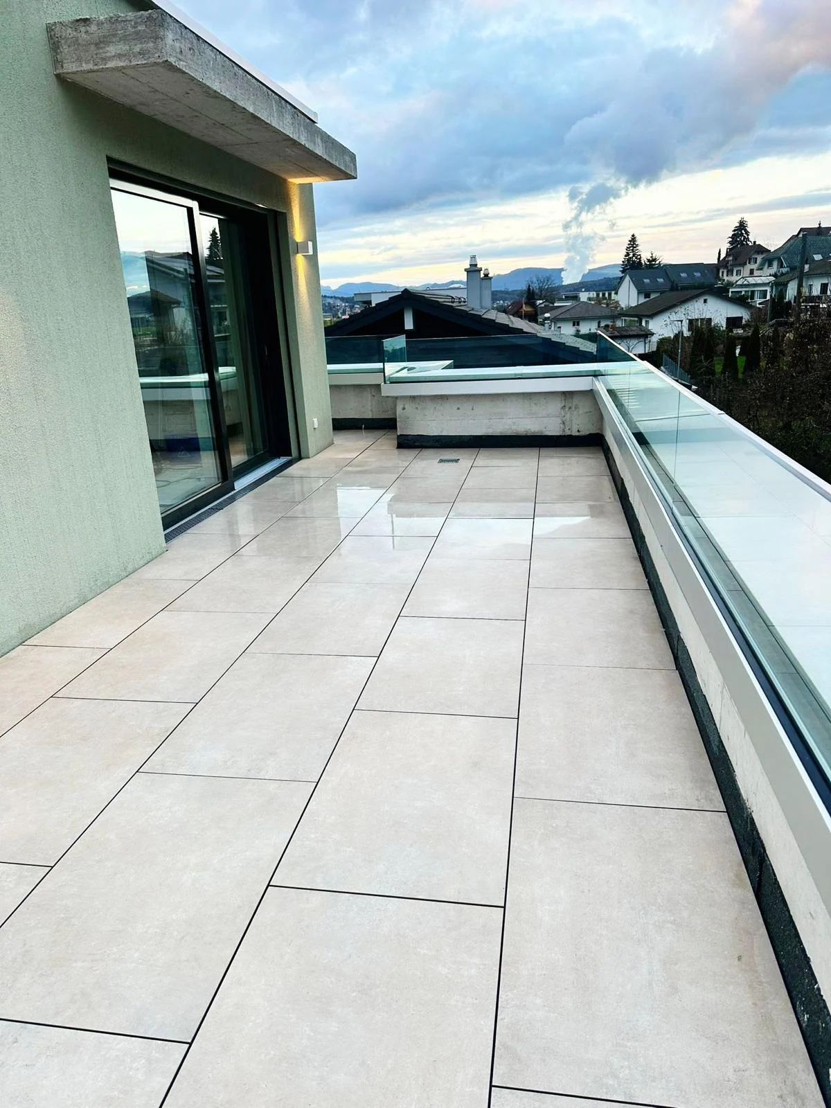 Heller Terrassenbelag hinter Glasgeländer