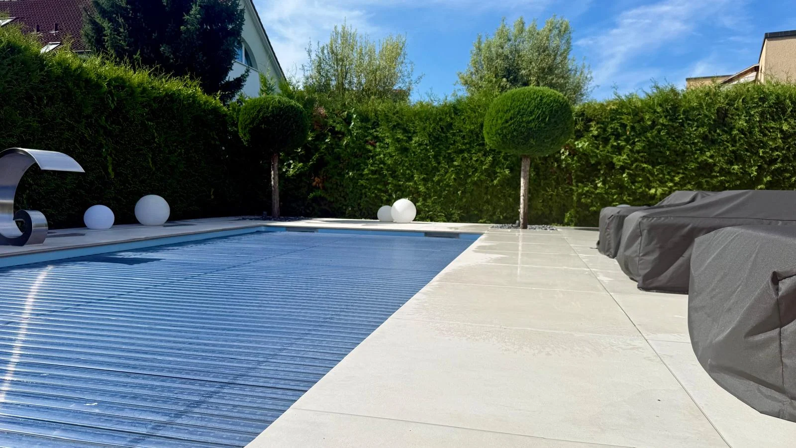 Poolabdeckung zwischen Terrasse und Formgehölzen