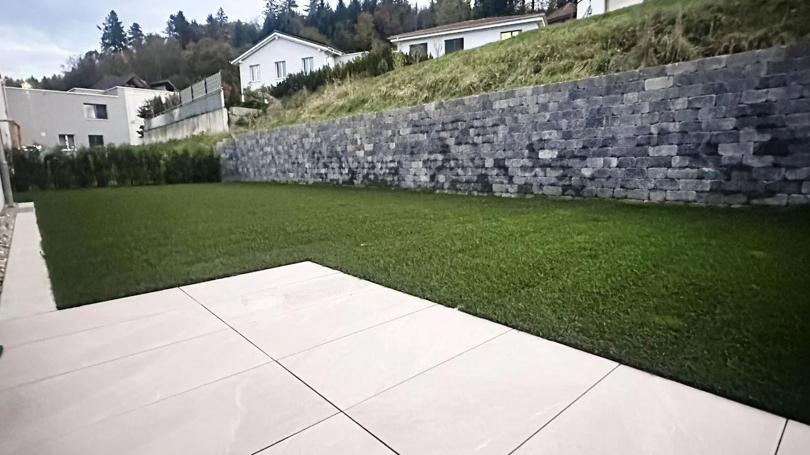 Rasenfläche vor hoher Stützmauer