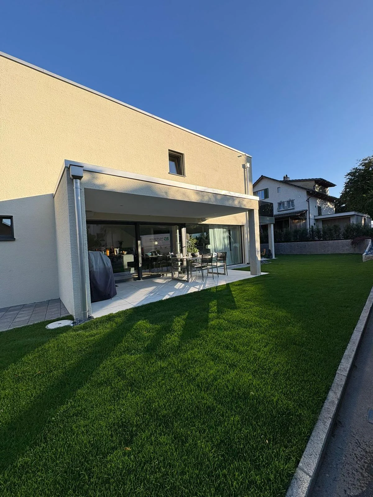 Satter Rasen vor überdachter Terrasse