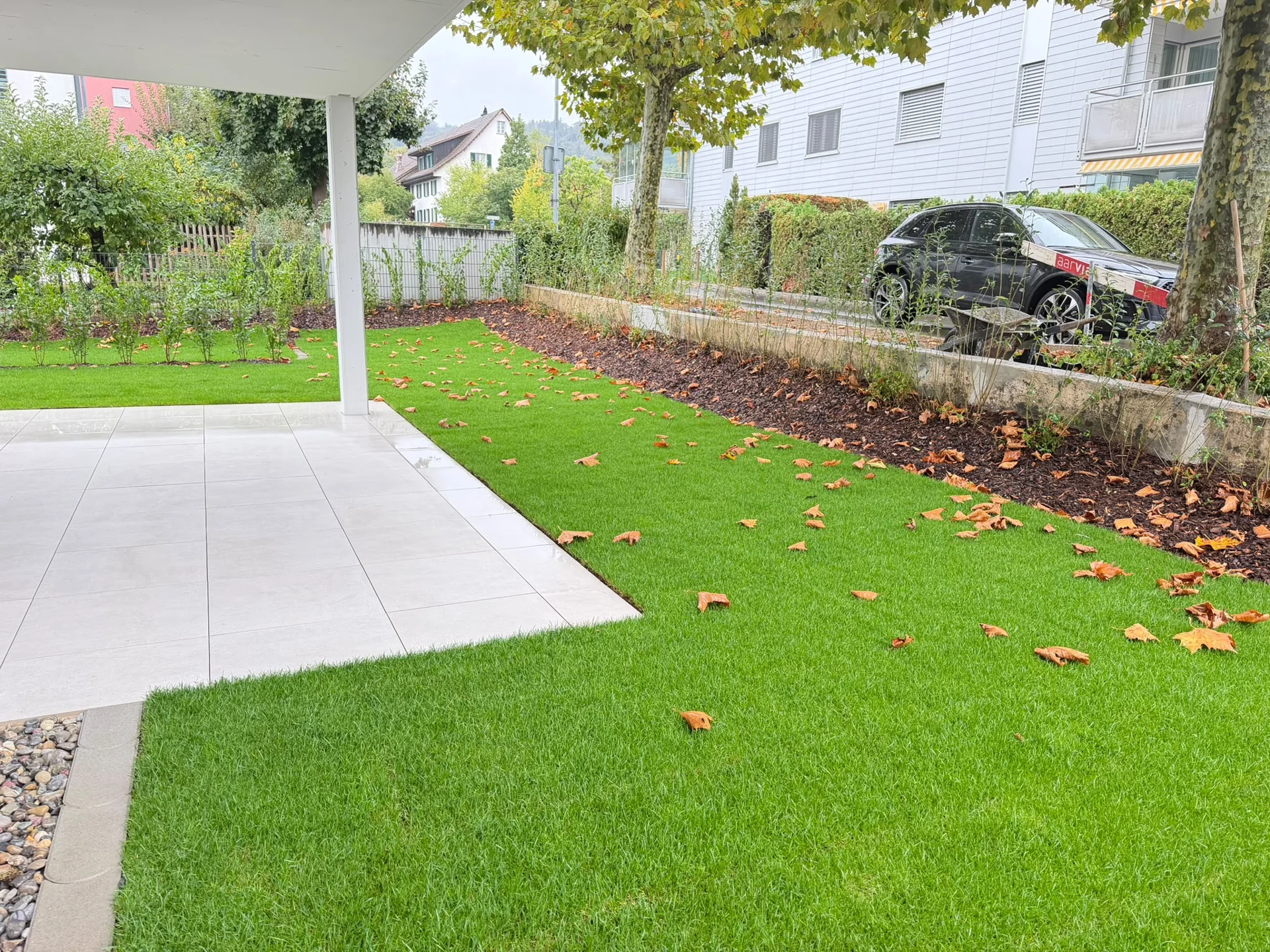 Überdachte Terrasse mit Rasen und Pflanzbeet