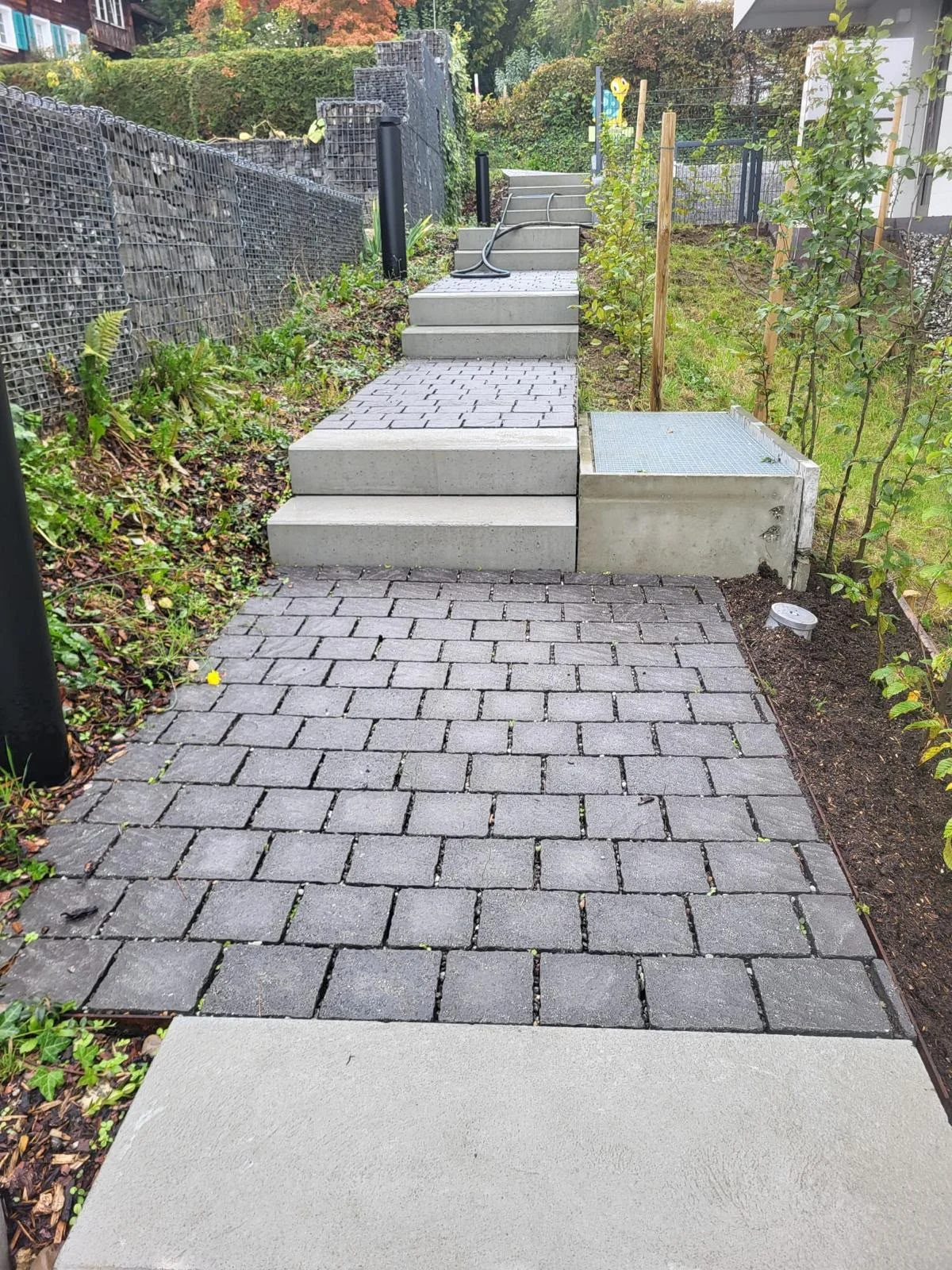 Gestufter Gartenweg entlang einer Gabionenwand